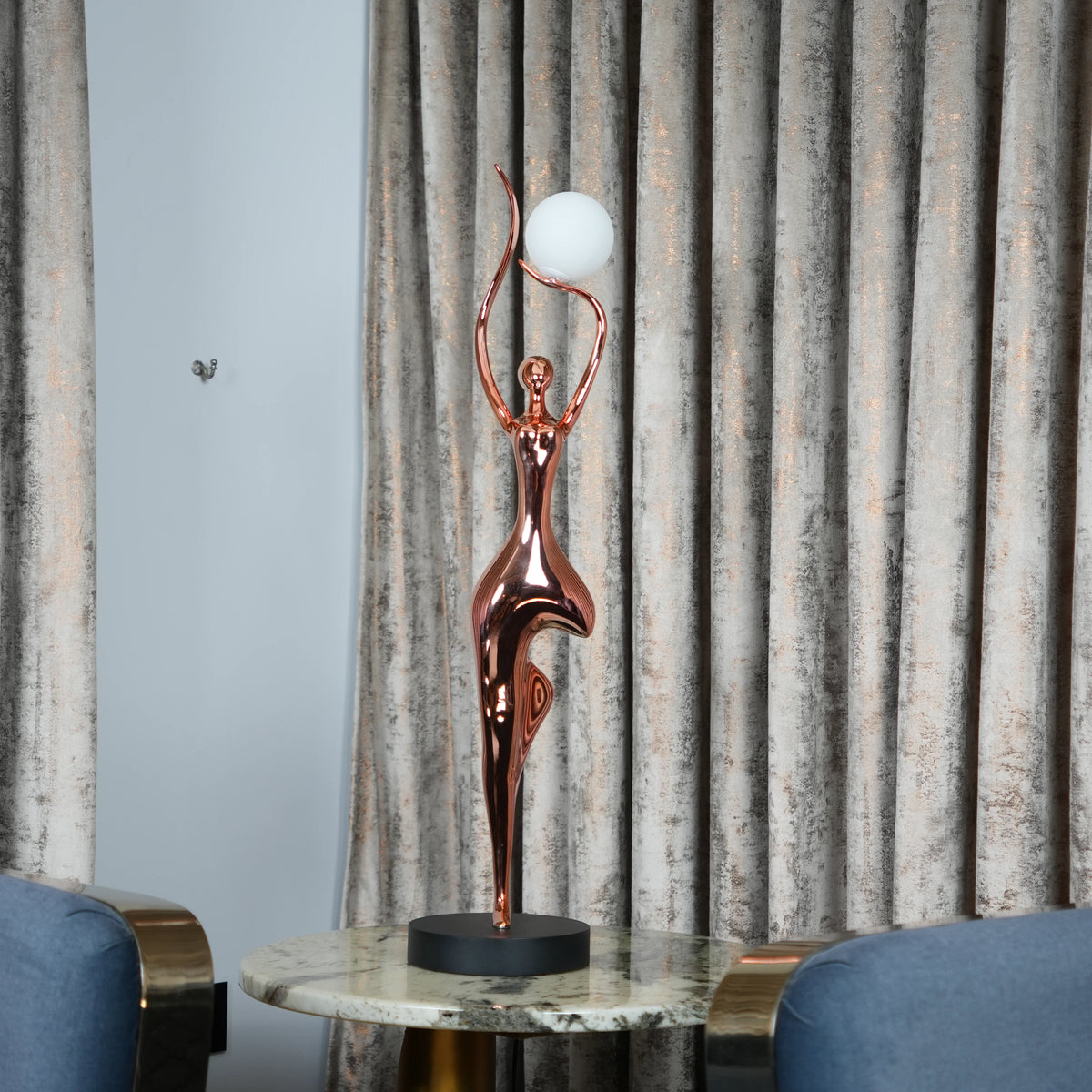 Rose gold lady lamp, marble between blue chairs