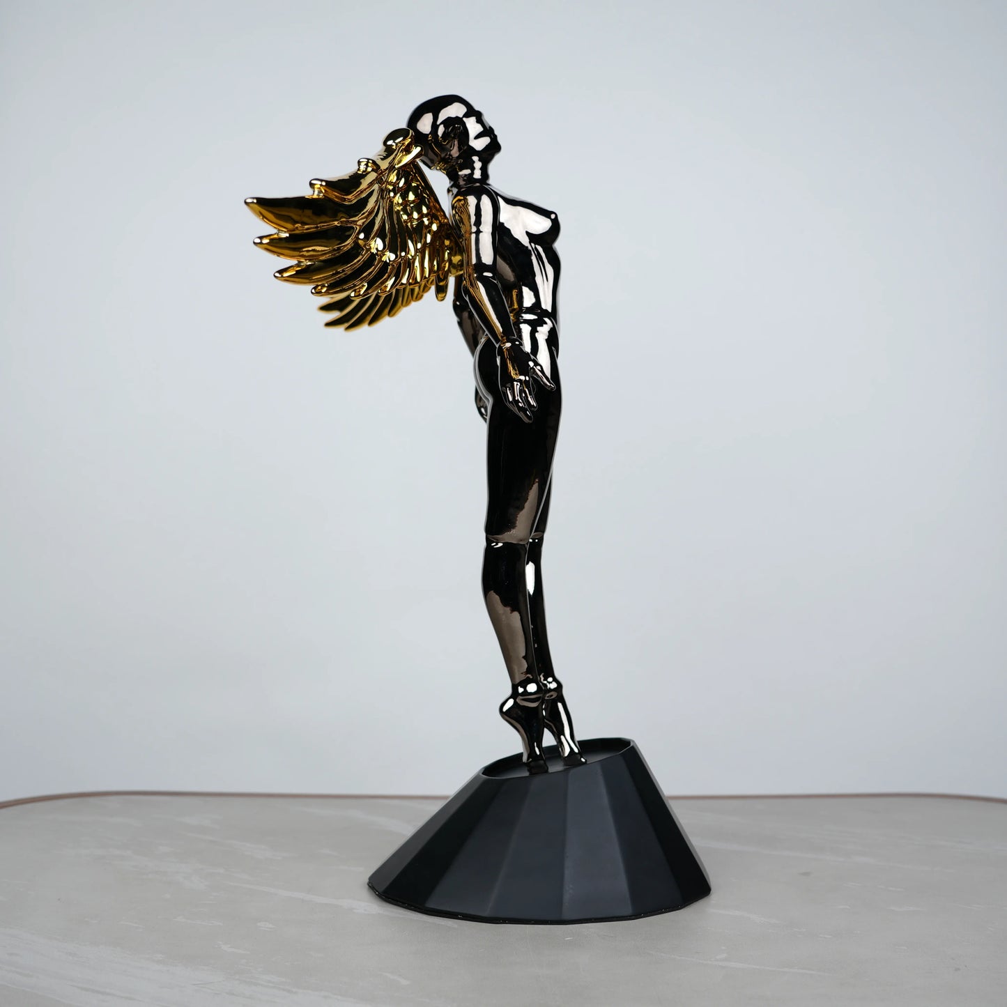 Celestial Chrome Angel Sculpture with reflective chrome body and gold wings on pedestal