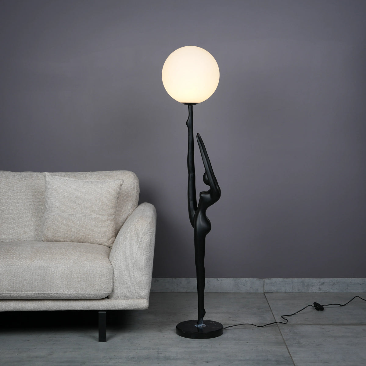 Elegant Human Stretch Lamp – tall matte black human-form sculpture holding a glowing orb floor lamp.