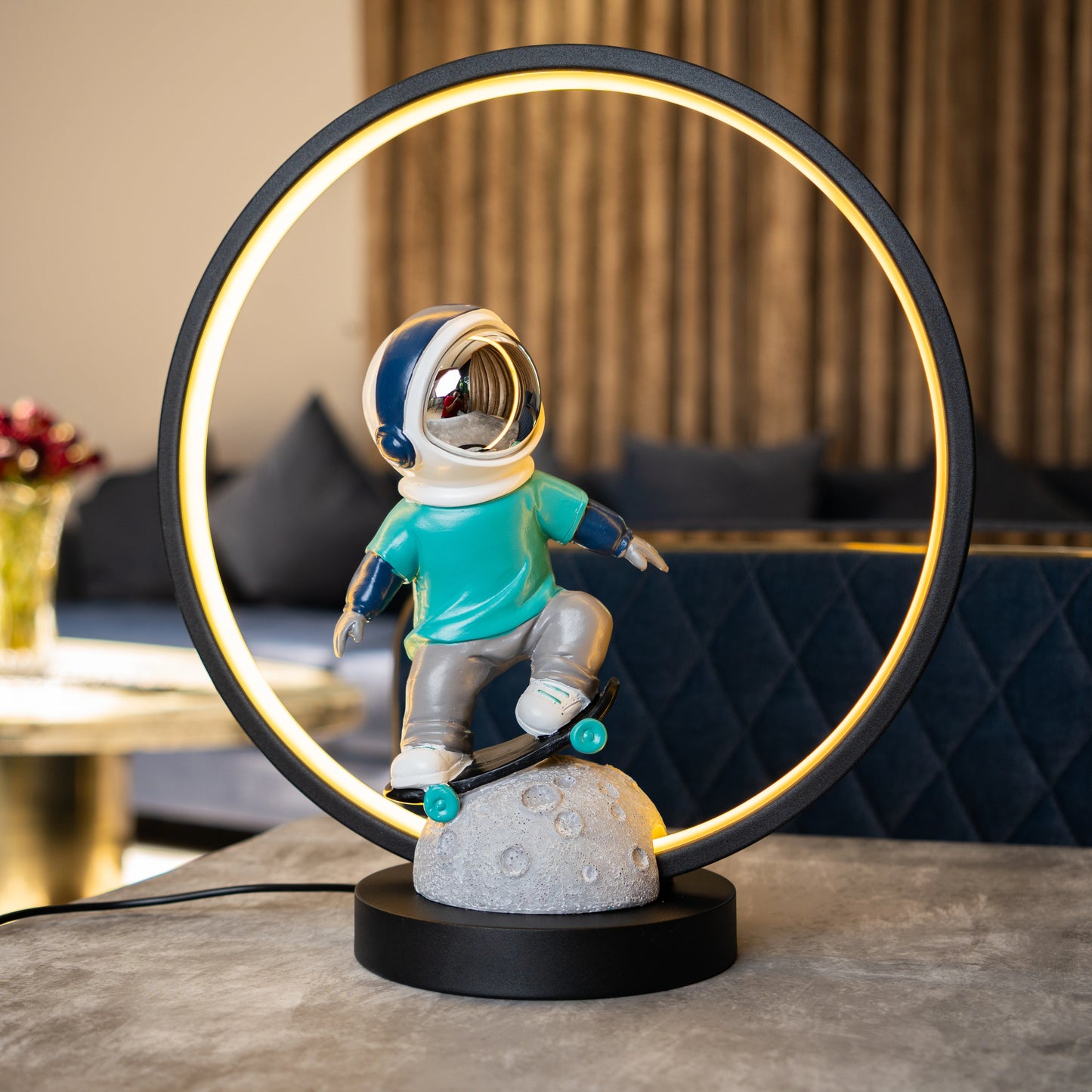 Astronaut skater lamp with teal suit, silver visor and LED ring on moon base