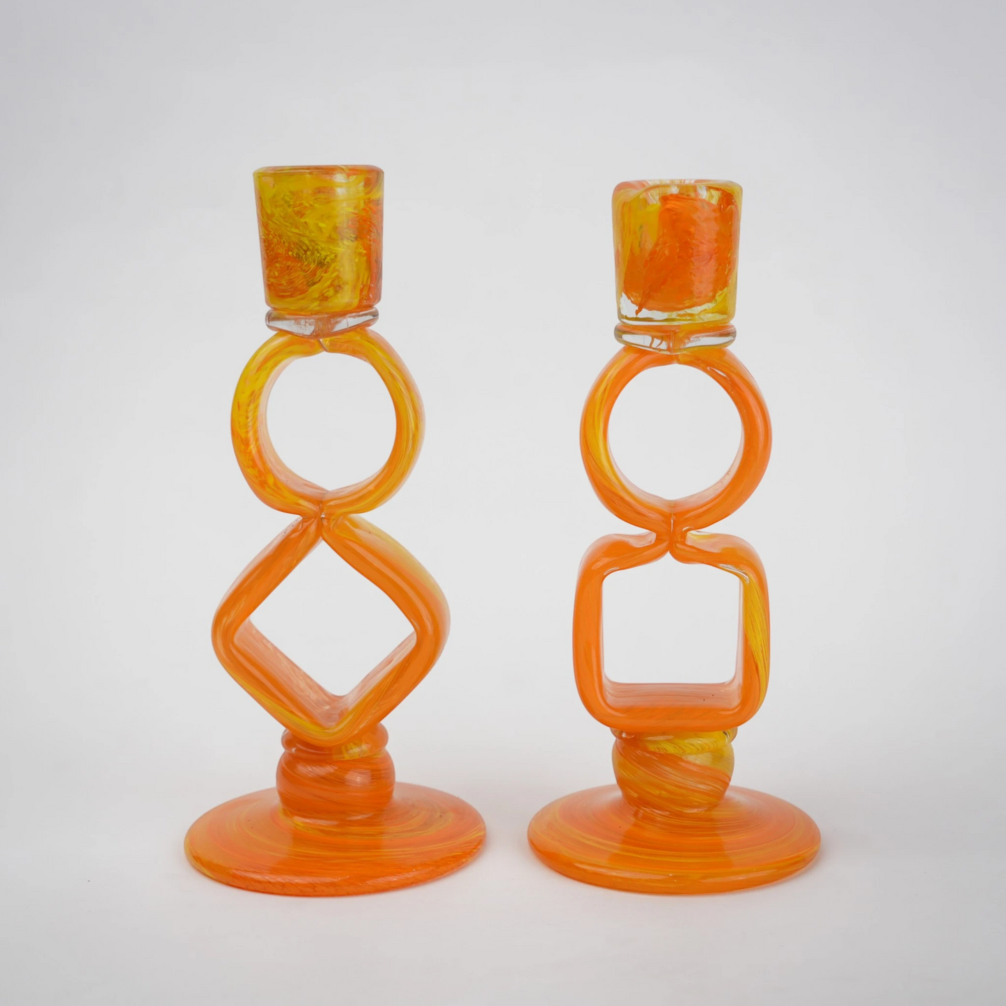 Orange art glass candle holder with geometric open frame and circular ring design
