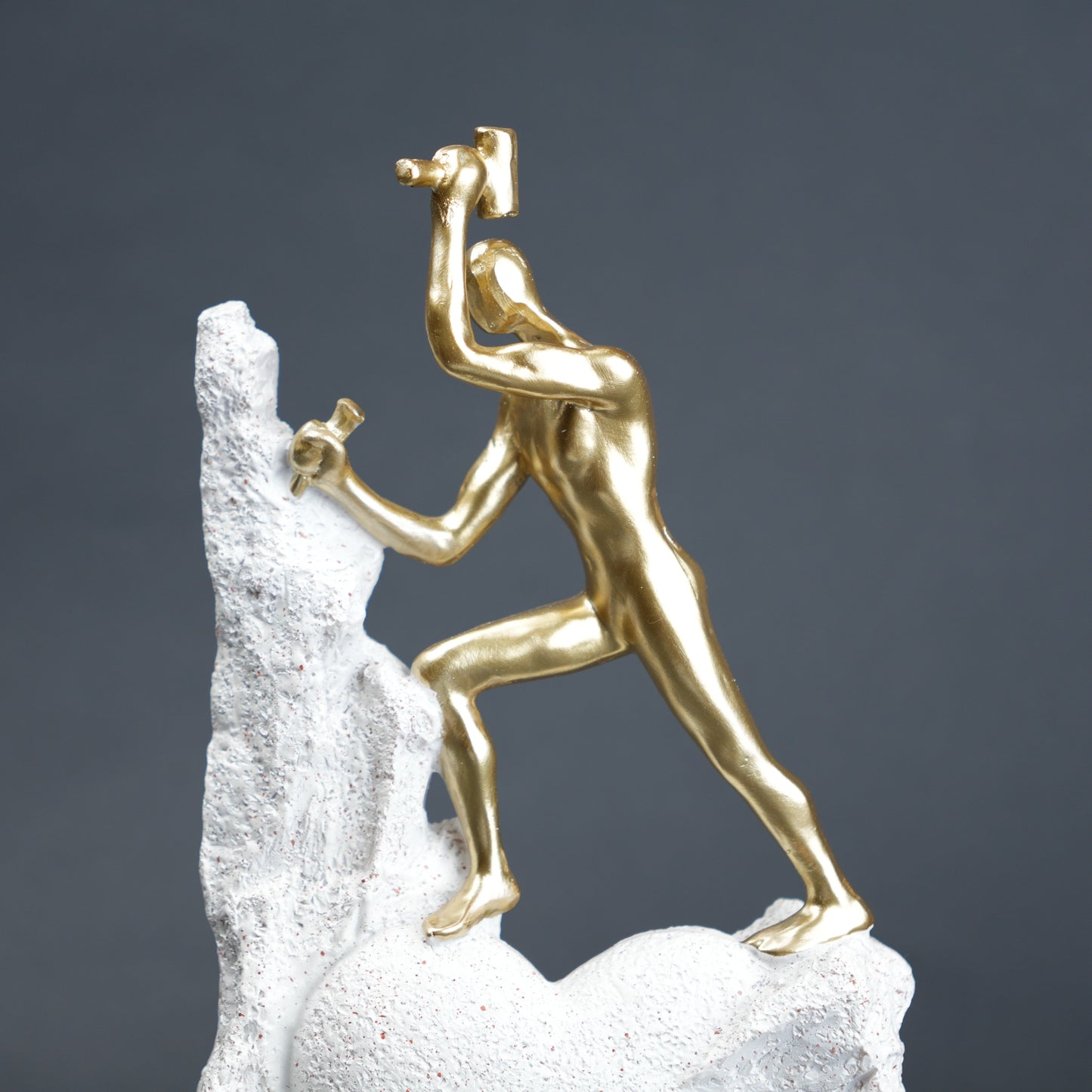 Teamwork climber figurine with gold figures pushing metallic sphere on textured rock base in black and white variants