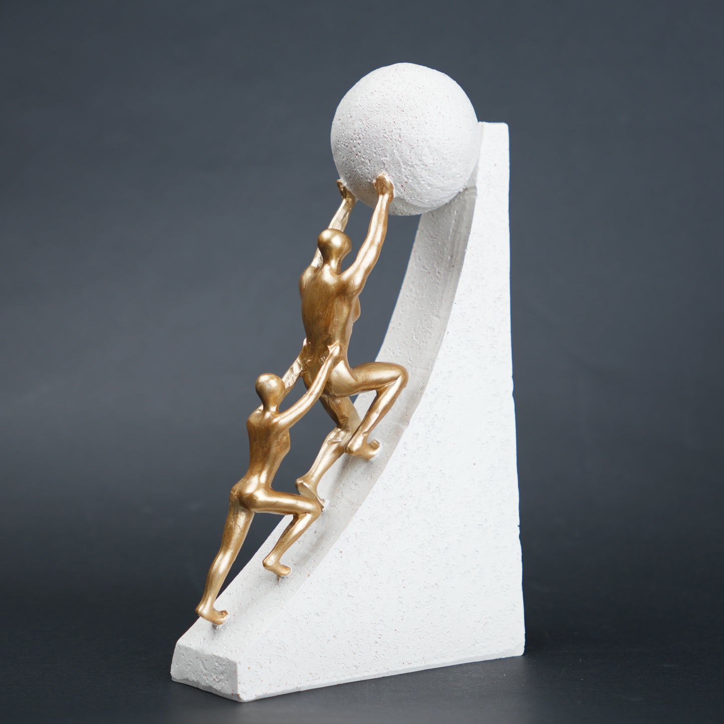 Mountain climber leadership sculpture with gold figurines guiding metallic sphere on textured stone base in black and white variants