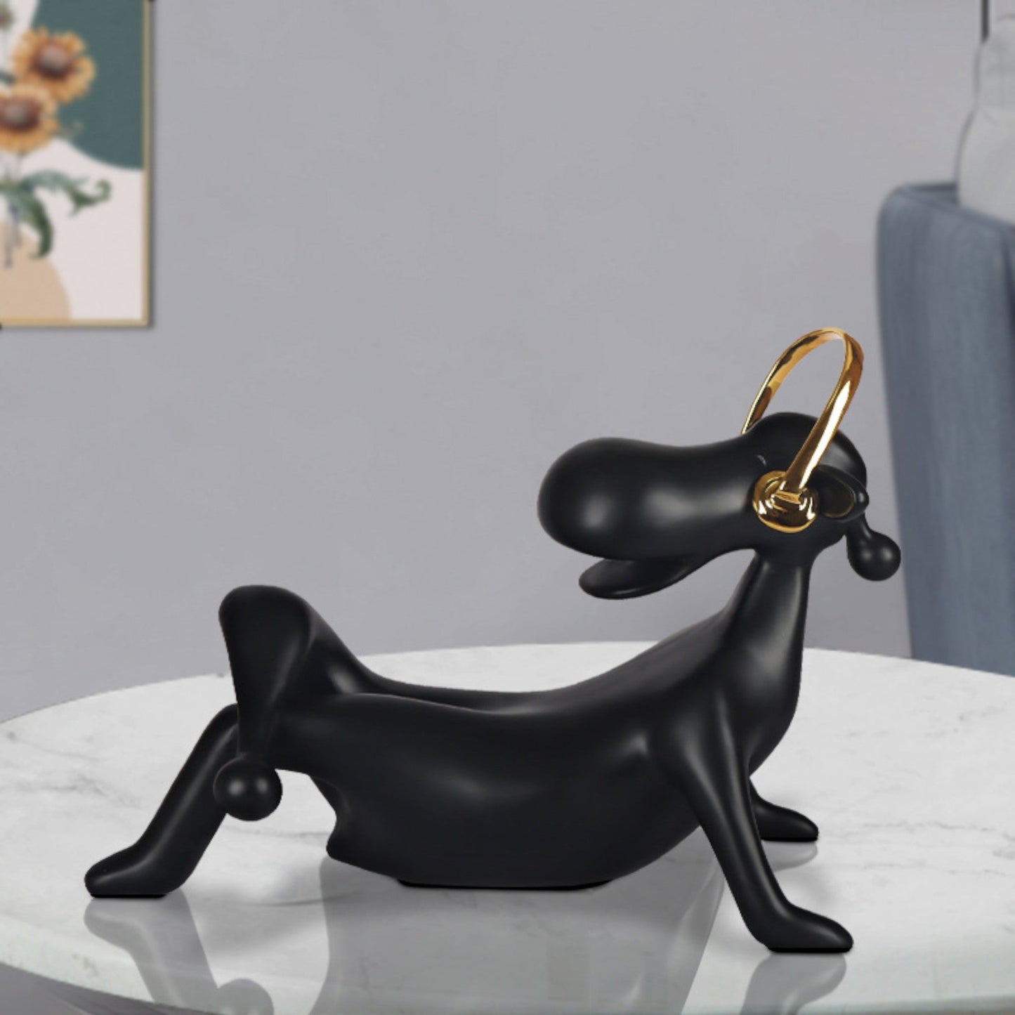 A black abstract figurine of an audiophile with a nan finish, featuring a looped golden element on top, placed on a white surface in a home environment.
