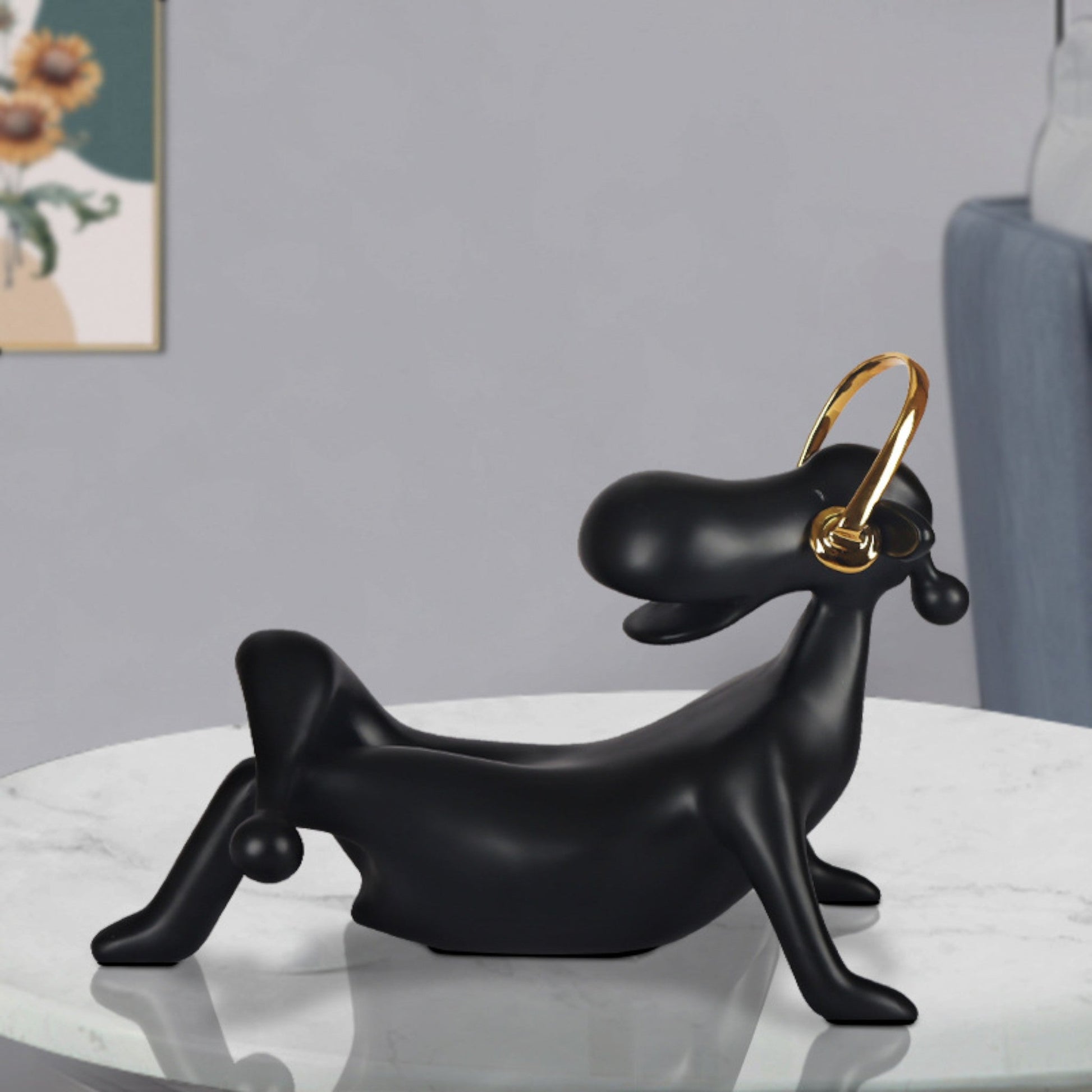 A black abstract figurine of an audiophile with a nan finish, featuring a looped golden element on top, placed on a white surface in a home environment.