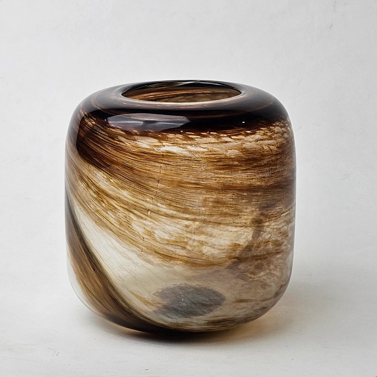A small cylindrical glass vase with a rounded rectangular shape, featuring a marbled swirl pattern of brown, beige, and black glass,
