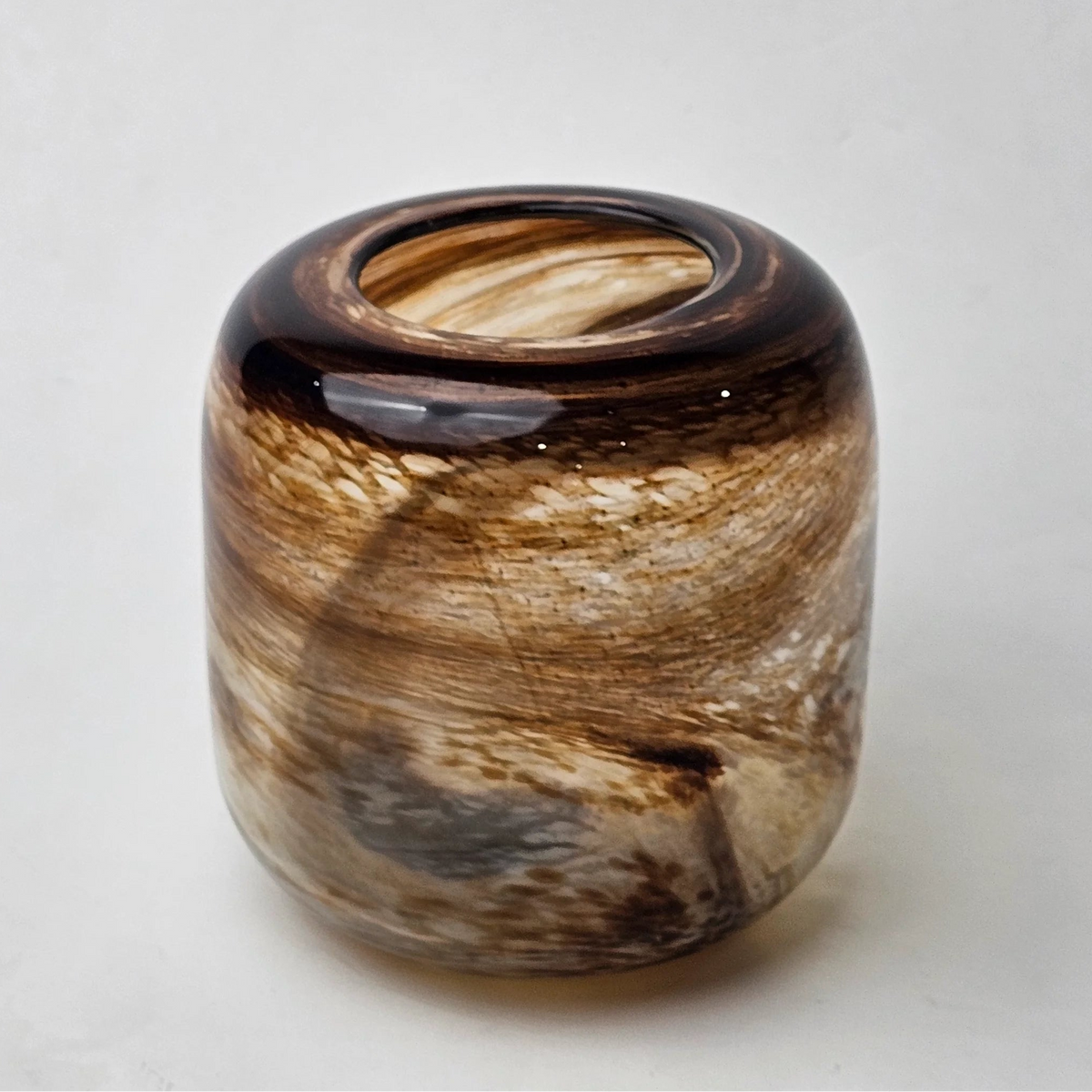 A small cylindrical glass vase with a marbled swirl pattern of brown, beige, and black