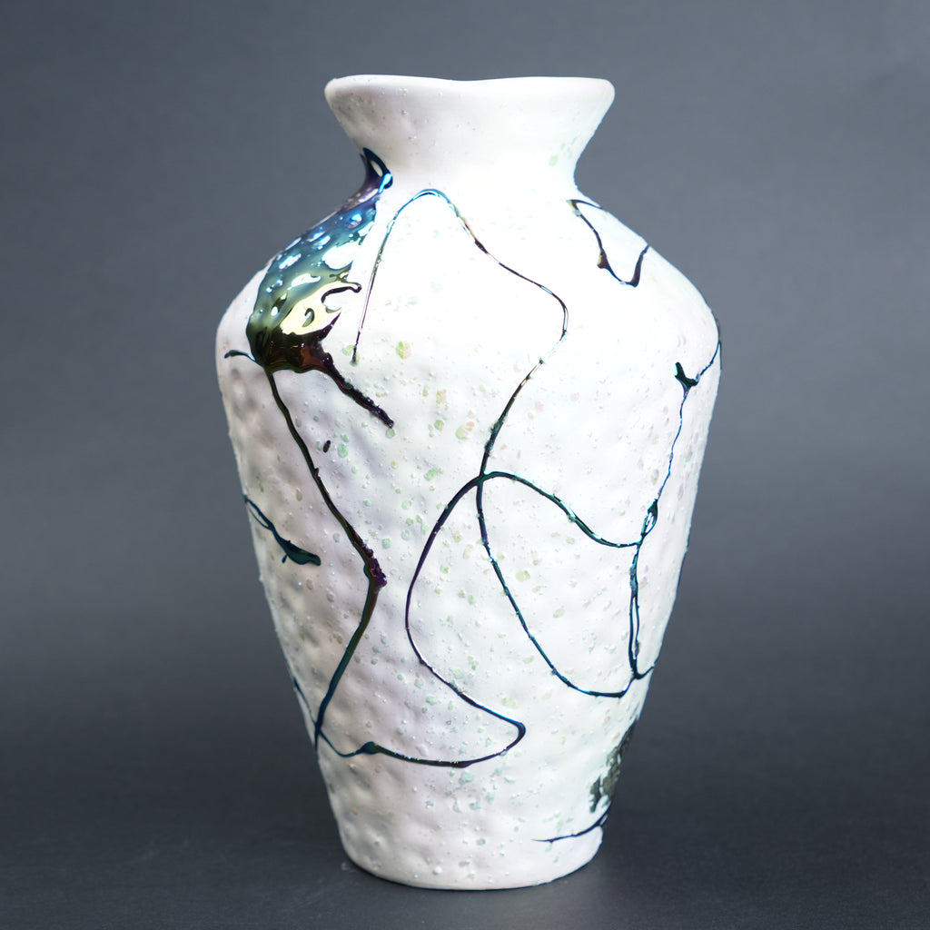 White ceramic vase with abstract black and blue designs on a gray background