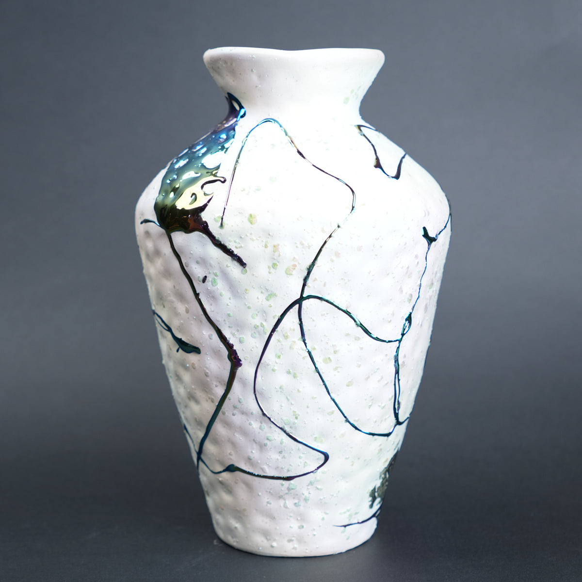 White ceramic vase with abstract black and blue designs on a gray background