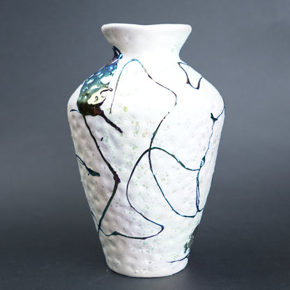 White ceramic vase with abstract black and blue designs on a gray background