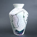White ceramic vase with abstract black and blue line art on a gray background