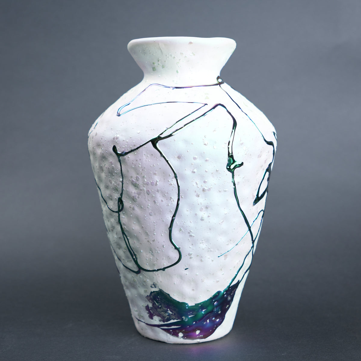 White ceramic vase with abstract black and blue line art on a gray background