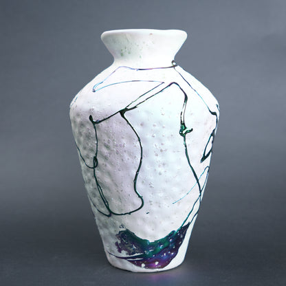 White ceramic vase with abstract black and blue line art on a gray background