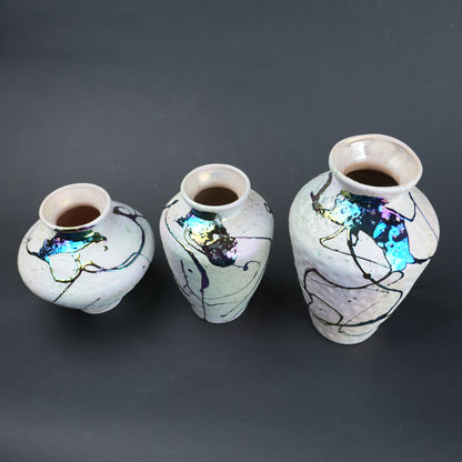 Three ceramic vases with abstract designs on a dark background