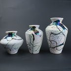 Three ceramic vases with abstract designs on a dark background