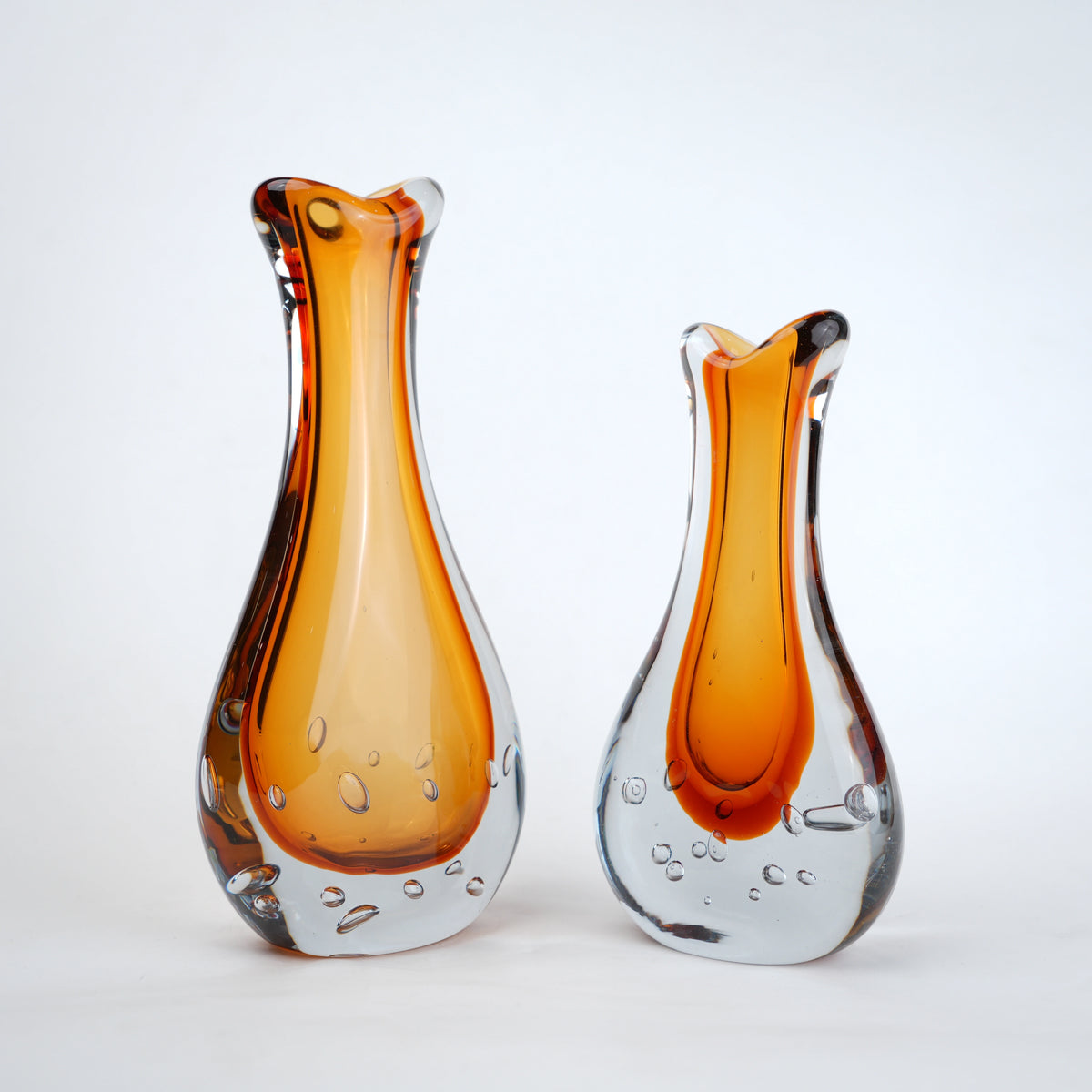 Amber clear art glass decorative vase with layered color center and elongated glass form.
