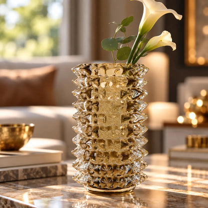 A textured, ribbed gold glass vase filled with white calla lilies, set on a polished marble coffee table in a warm, modern living room.
