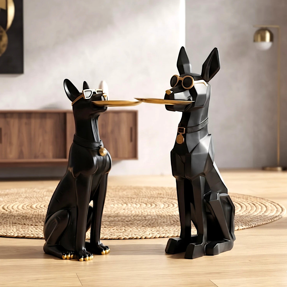 Two modern black dog statues with gold accents and sunglasses, posed facing each other on a light wood floor in a styled interior setting.