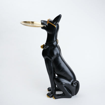 A glossy black dog figurine sitting upright and holding a small gold tray in its mouth, with gold accents on the collar and tray, photographed against a clean white background.