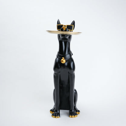 A glossy black cat figurine wearing a beige hat with gold trim and sunglasses, plus a black collar with a gold bell, posed against a clean white background.