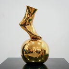Gold ceramic vase featuring artistic foot design on spherical base