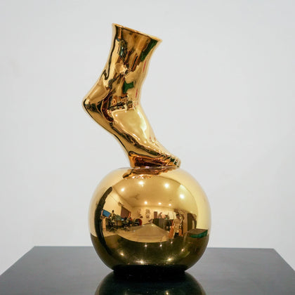 Gold ceramic vase featuring artistic foot design on spherical base