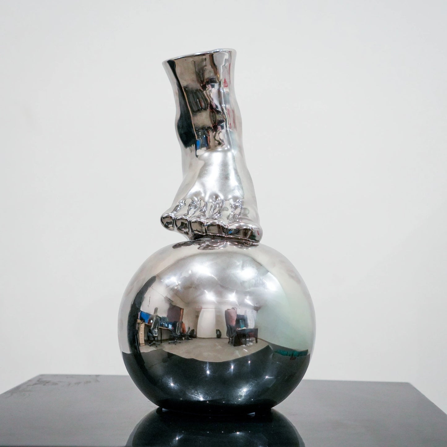 Silver ceramic vase featuring artistic foot design on spherical base