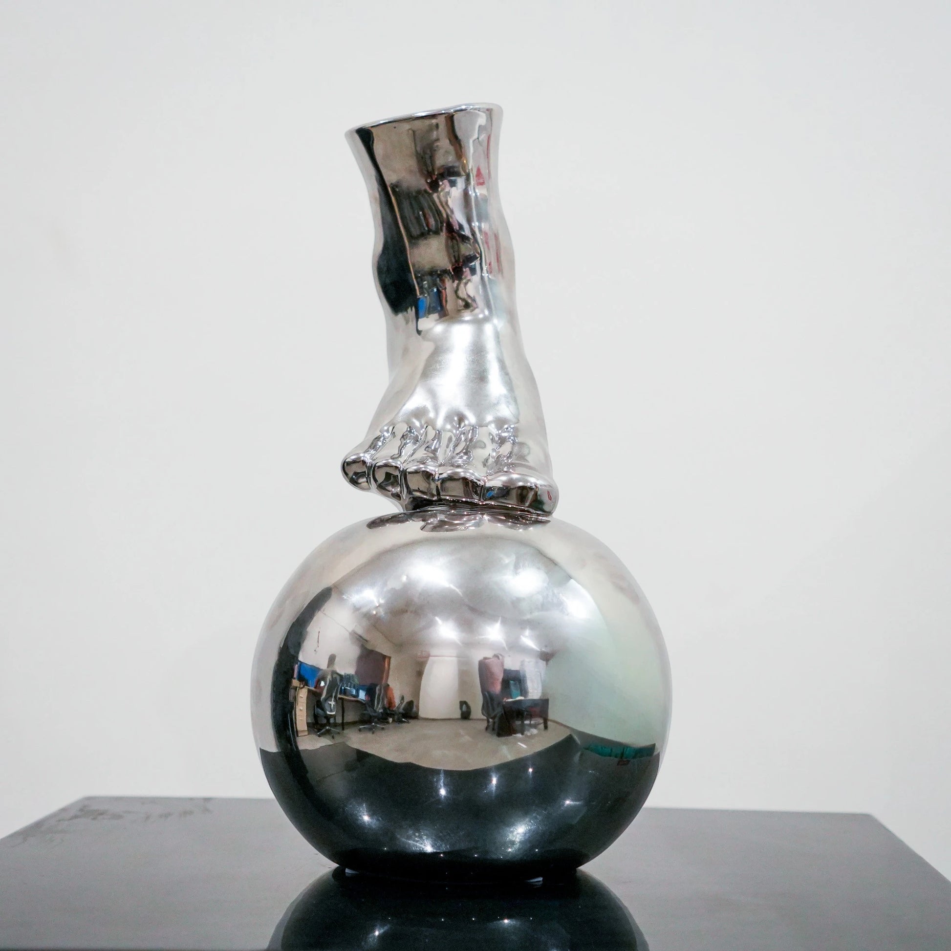 Silver ceramic vase featuring artistic foot design on spherical base