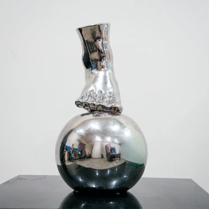 Silver ceramic vase featuring artistic foot design on spherical base