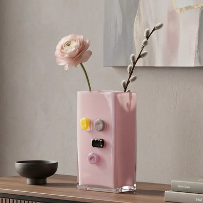 Pink art glass vase with embedded multicolor accents and wide rectangular form.