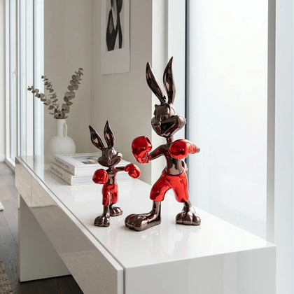 Decorative boxing rabbit statues on a white surface with a modern interior background
