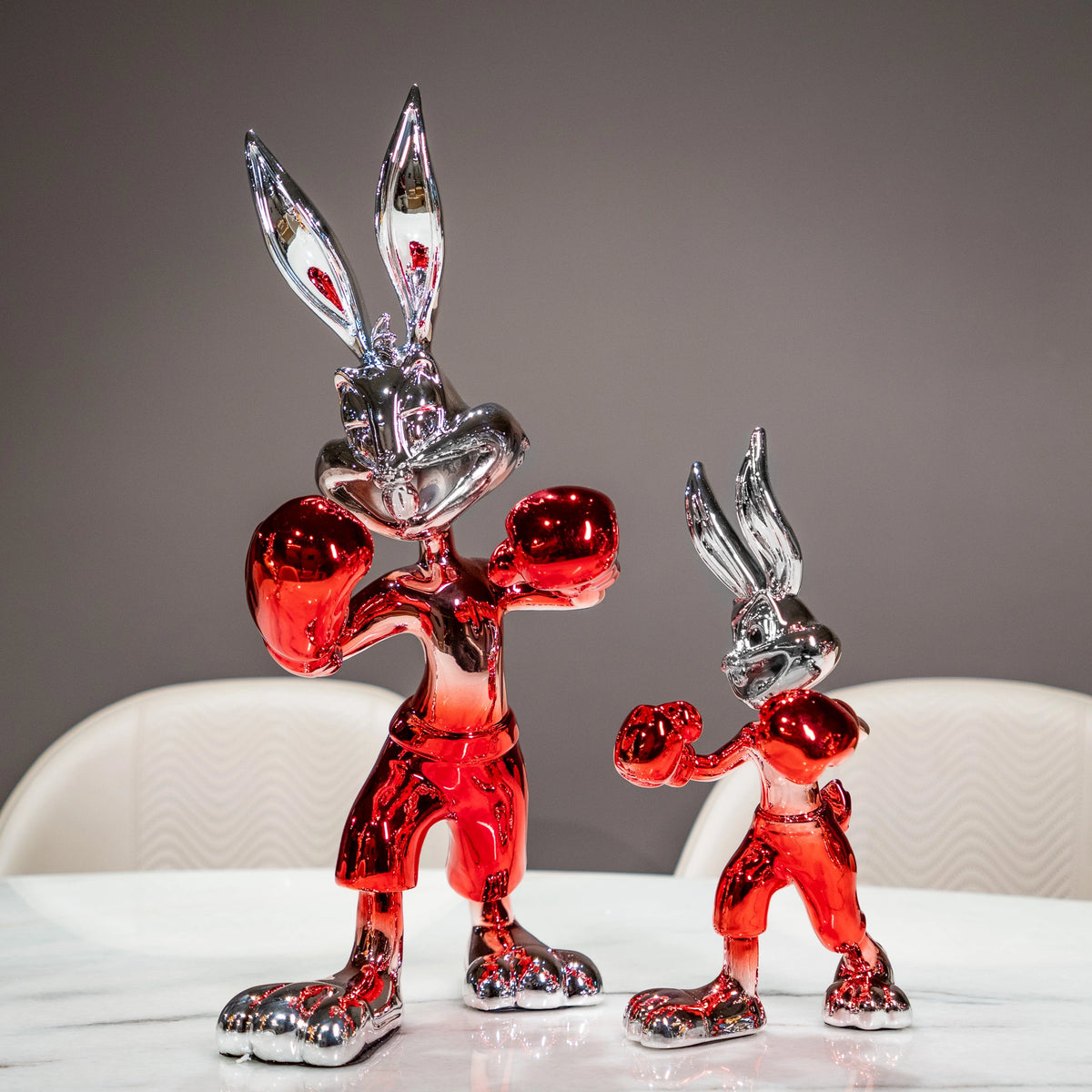 Two metallic red and silver rabbit figures on a white background