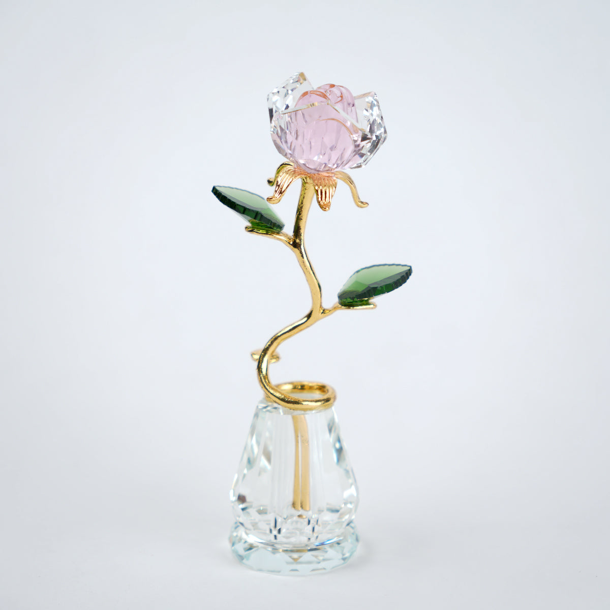 Decorative crystal flower with gold stem and pink petal on a clear base against a white background