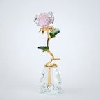 Decorative glass rose with pink gemstone on a white background