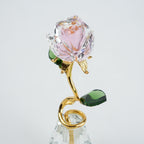 Crystal rose with gold stem and green leaves on a light gray background