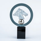 A modern glass sculpture award trophy featuring a clear glass horse head profile inside a circular frame, mounted on a polished silver sphere and a glossy black rectangular base.