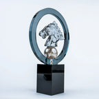 A modern glass and metal trophy featuring a polished silver horse head sculpture inside a dark blue-gray circular frame, mounted on a glossy black rectangular base against a light gray studio background.