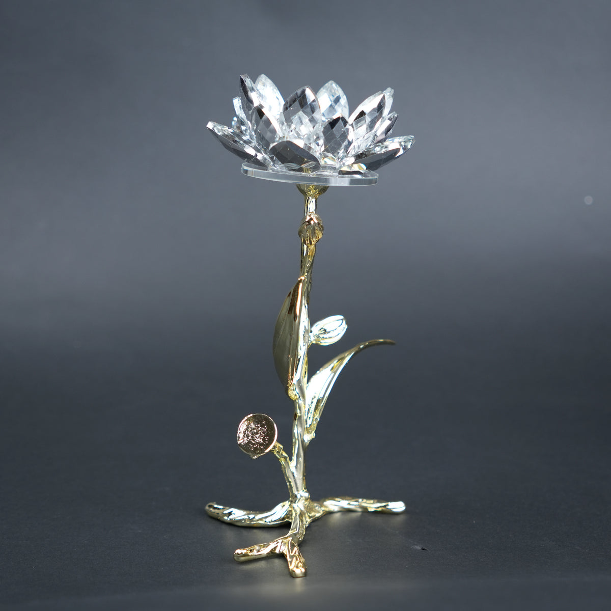 Decorative crystal object on a gold stand against a dark background
