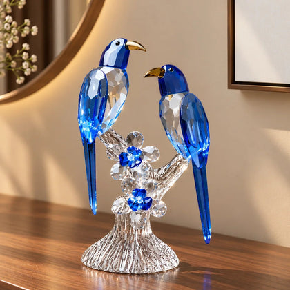 A decorative figurine of two yellow birds perched on a clear crystal branch with small yellow flowers