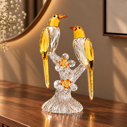 A decorative figurine of two yellow birds perched on a clear crystal branch with small yellow flowers