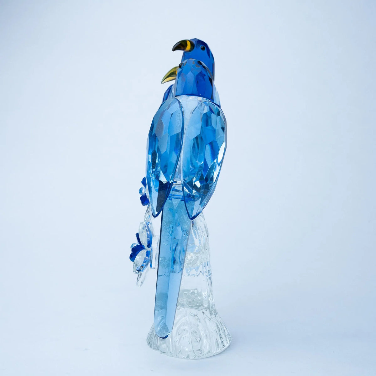 A blue crystal bird figurine standing on a clear textured base 