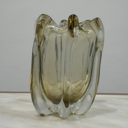 Decorative sculptural glass vase featuring fluid architectural curves and elegant translucent finish for modern living spaces