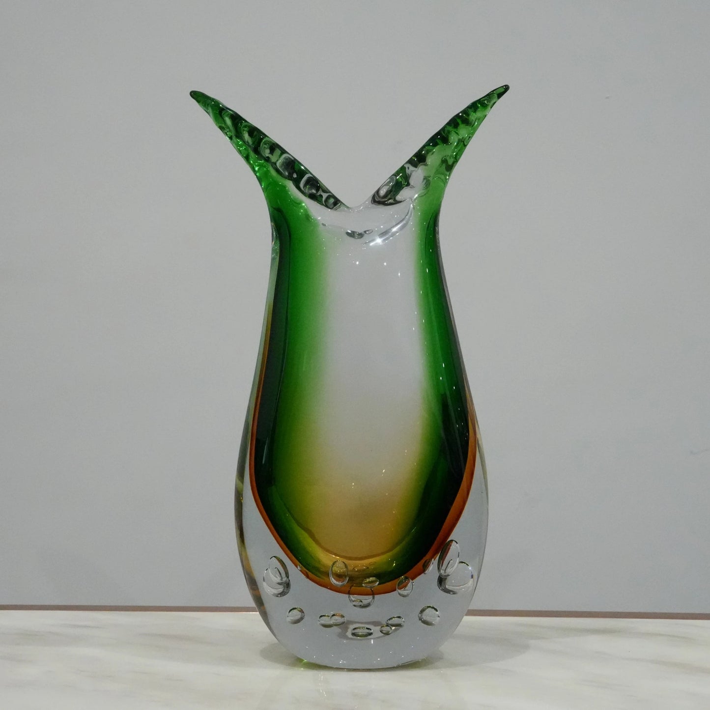 Handblown artistic glass vase with flowing horn silhouette, bubble detailing and green amber gradient finish for luxury modern decor