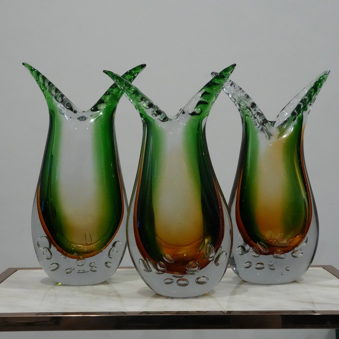 Handblown artistic glass vase with flowing horn silhouette, bubble detailing and green amber gradient finish for luxury modern decor