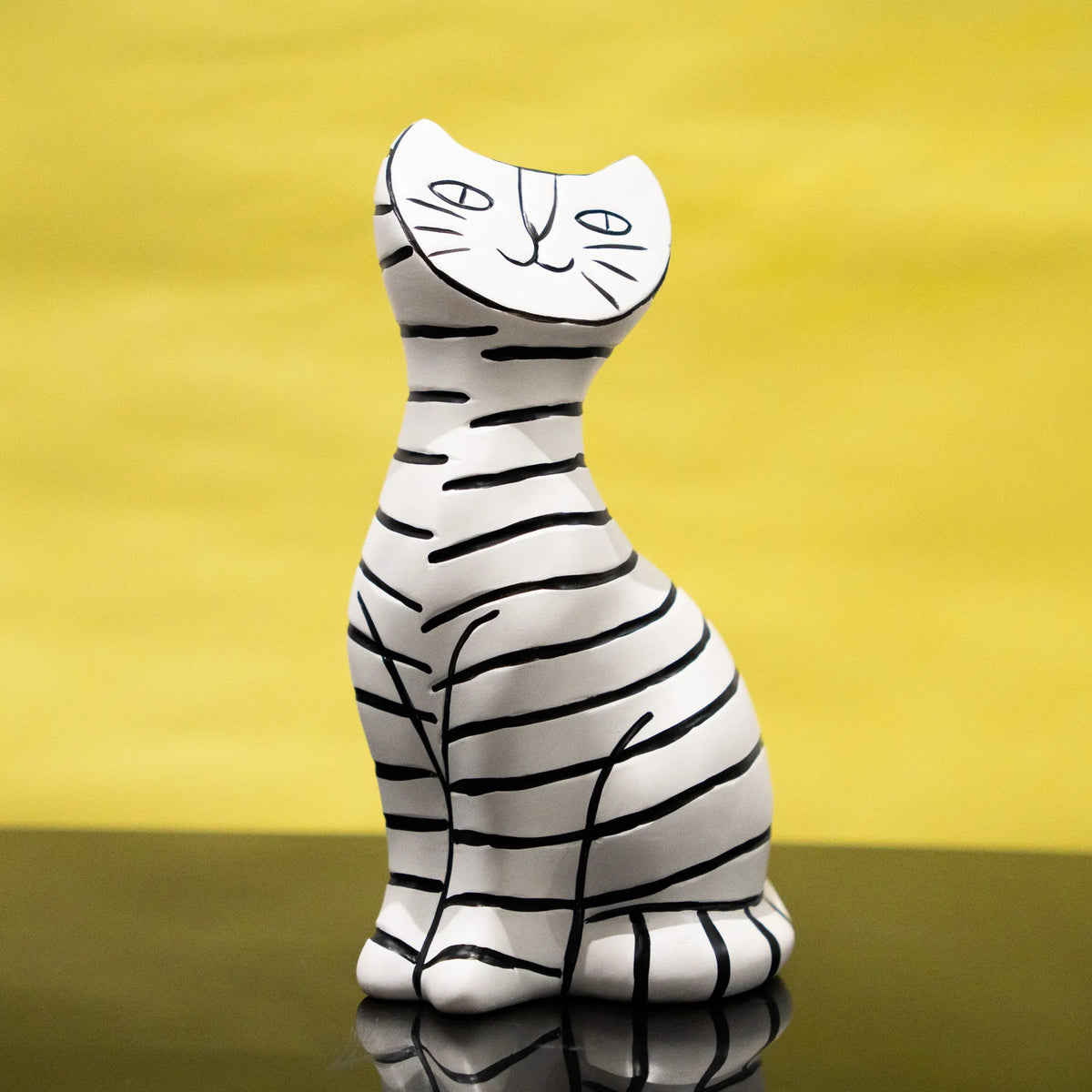 A resin cat figurine with a white base and black hand-drawn stripes.