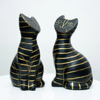 Two black cat figurines with gold stripes, one facing left and one facing right, displayed on a white surface against a white background.