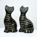 Two black cat figurines with gold stripes and gold line details on their faces, displayed side by side on a white surface against a white background.