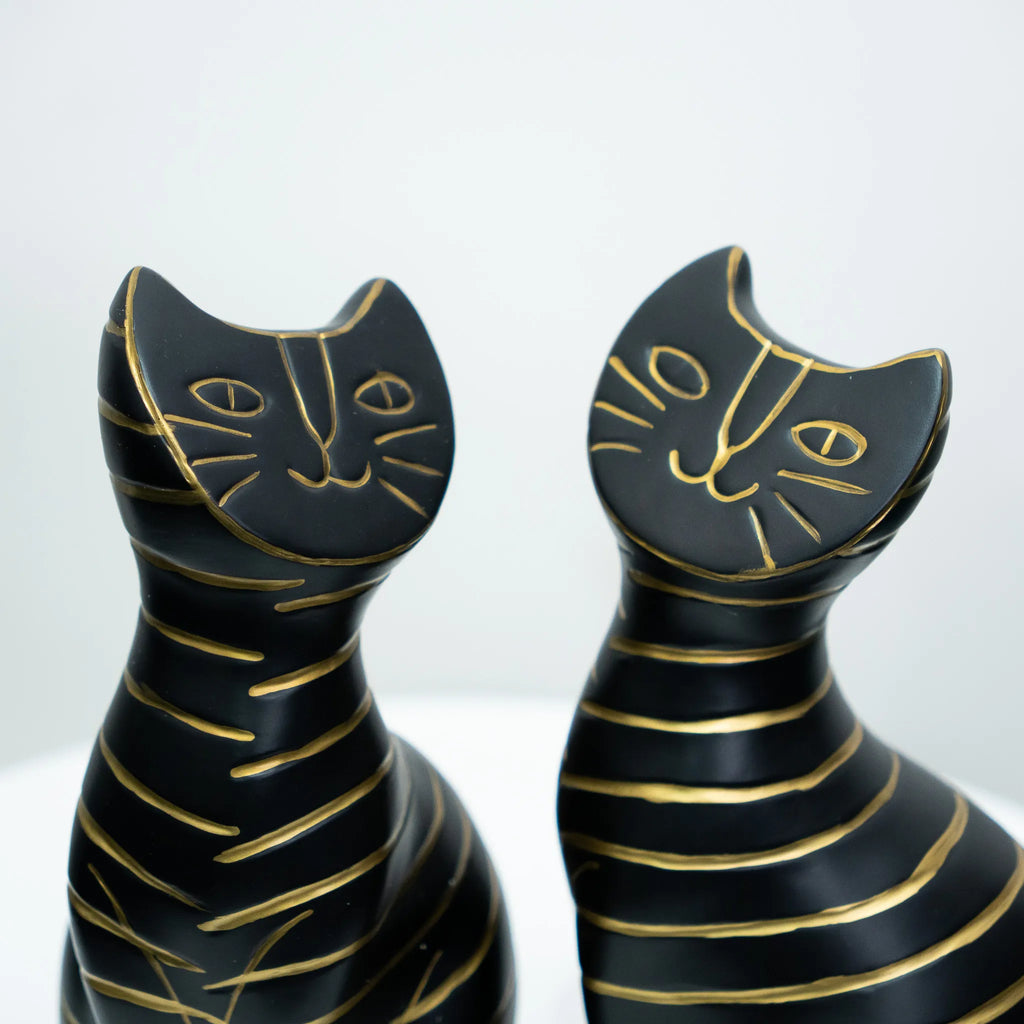Two black cat-shaped decorative sculptures with gold line details, shown against a clean white background.