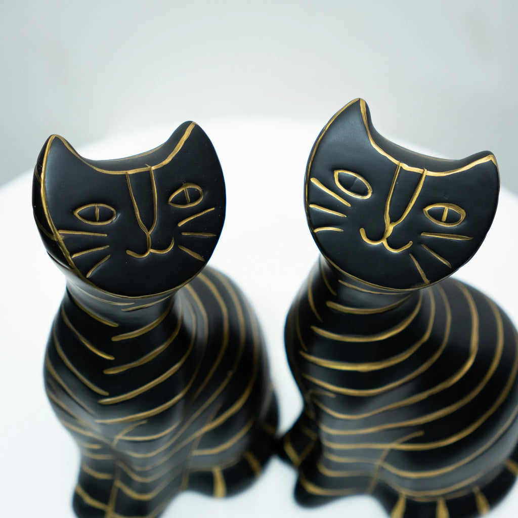 Two black cat-shaped decorative figurines with gold line details, shown on a light gray background.