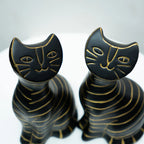 Two black cat-shaped decorative figurines with gold line details, shown on a light gray background.